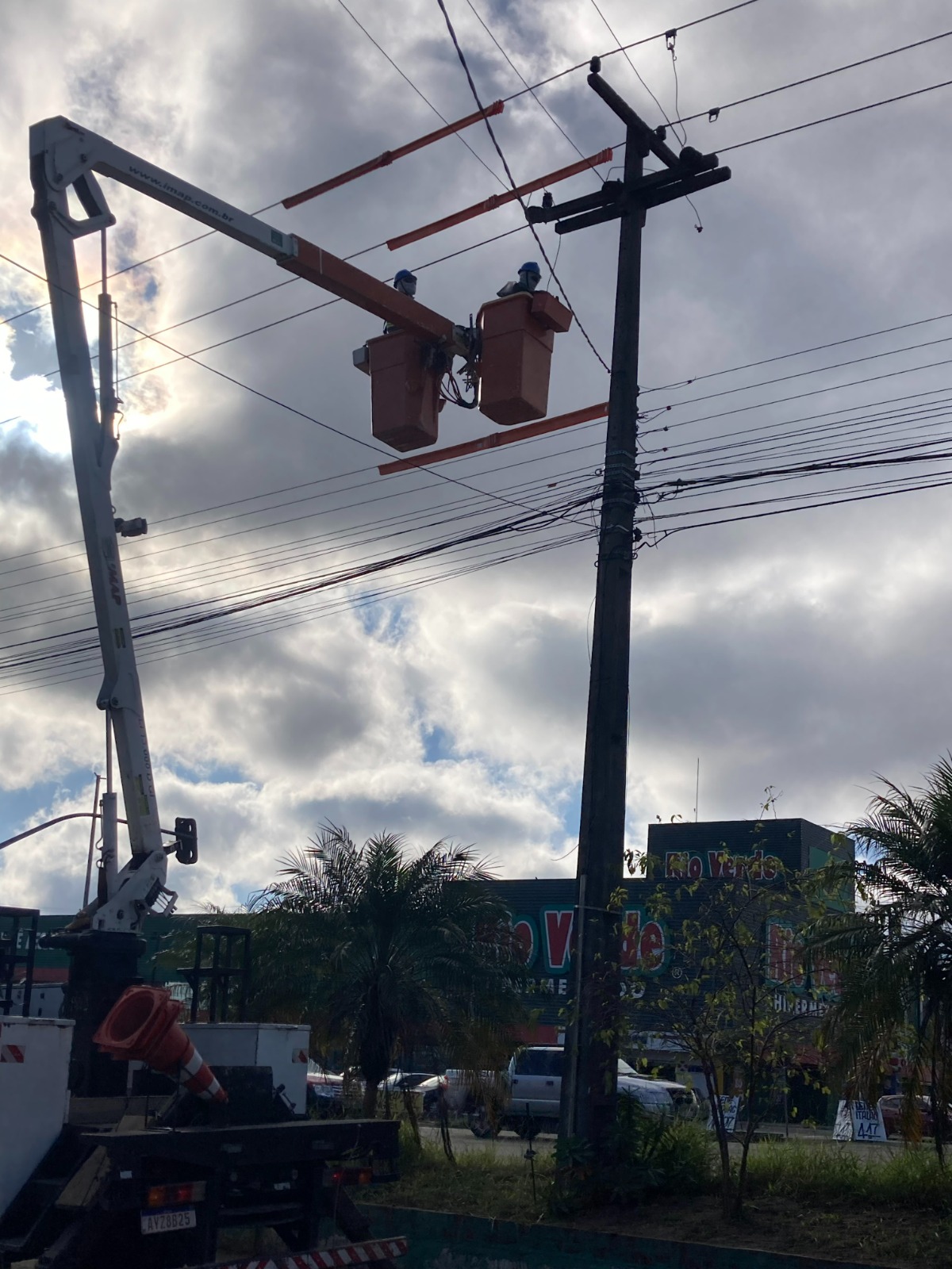 Equipe em cesto aéreo de caminhão executando manutenção elétrica em rede de distribuição
