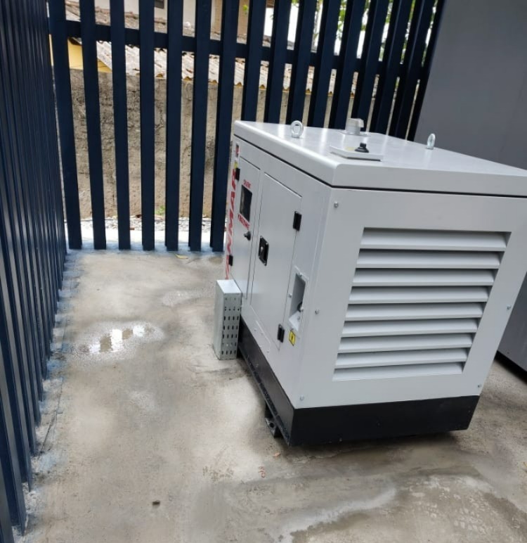 Gerador de energia enclausurado instalado em área externa protegida por grade